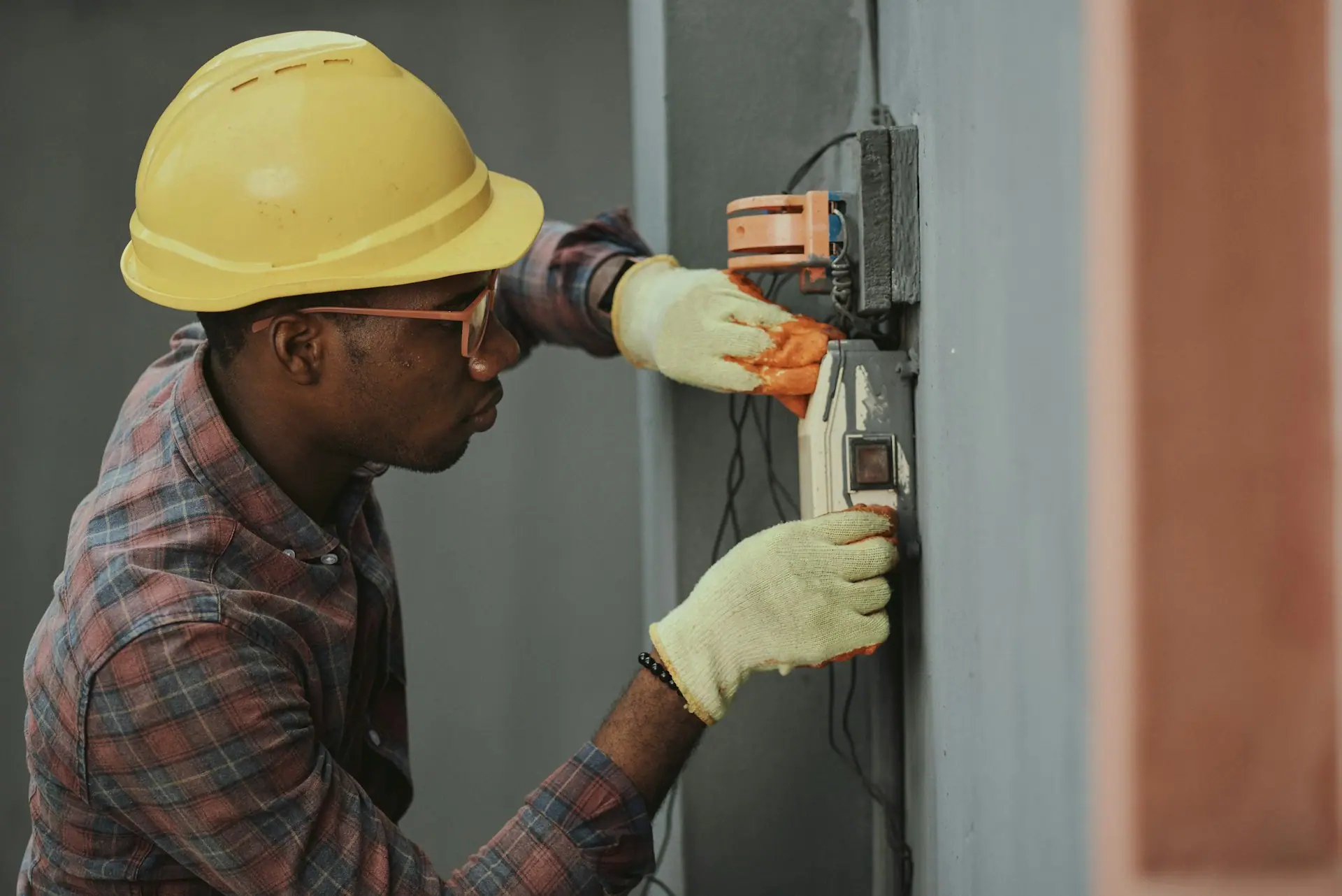 Electrician in a hard hat working on a wall panel